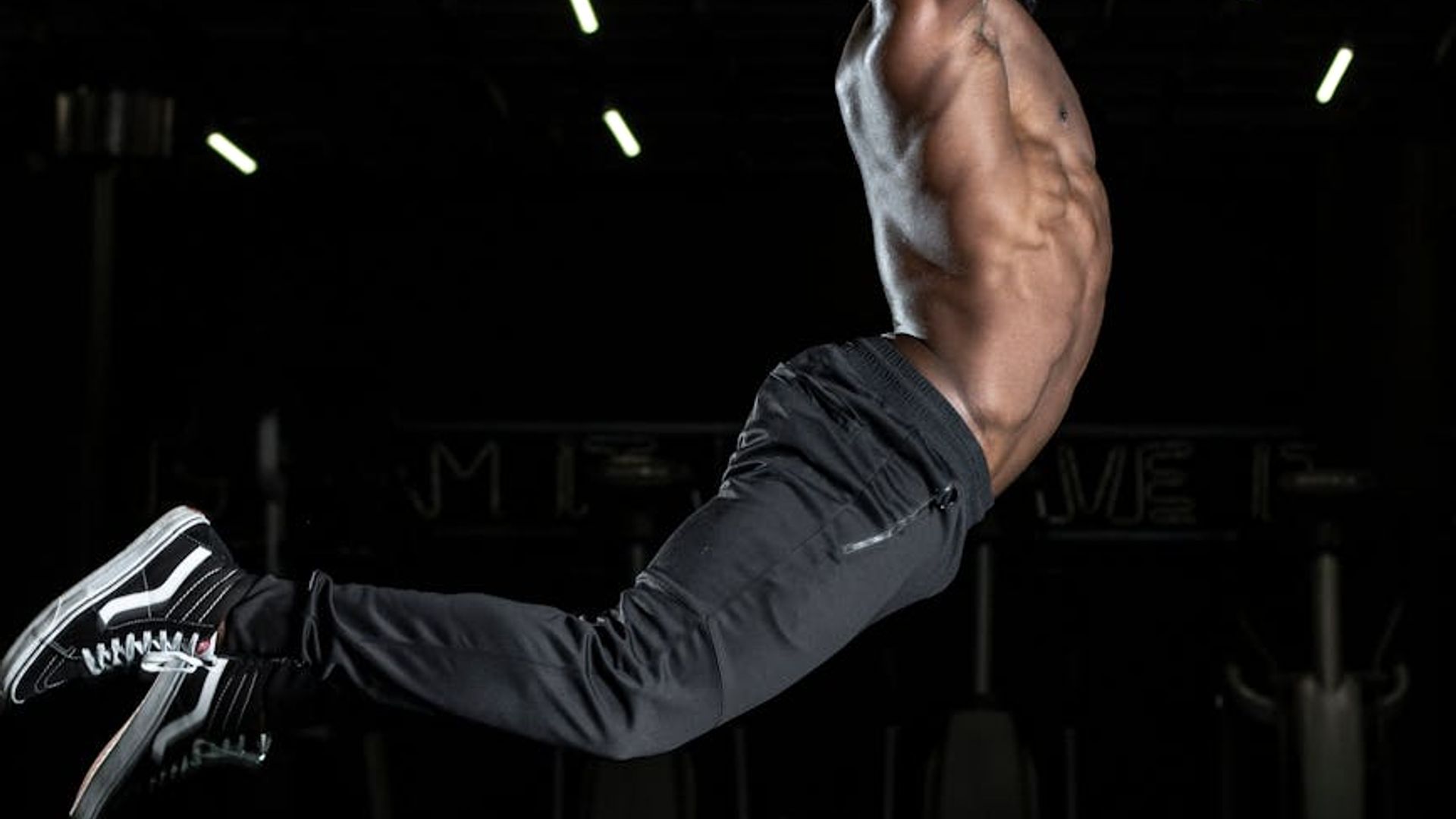 Person performing dynamic cardio movements in a dark studio.